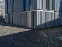 cobblestone driveway surrounded by modern buildings on sunny day with sun reflecting onto the windows