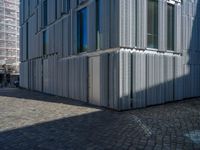 cobblestone driveway surrounded by modern buildings on sunny day with sun reflecting onto the windows