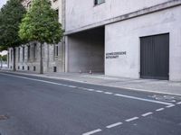 the entrance to an outside garage in a large building next to a tree lined street
