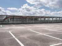 train in the middle of a parking lot with no people on it and cloudy skies above