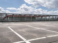 train in the middle of a parking lot with no people on it and cloudy skies above