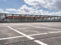 train in the middle of a parking lot with no people on it and cloudy skies above