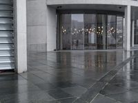 a black umbrella sitting outside the entrance to a building with many doors opened on the side