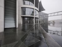 a black umbrella sitting outside the entrance to a building with many doors opened on the side