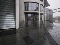 a black umbrella sitting outside the entrance to a building with many doors opened on the side