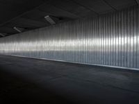 an industrial building features high ceiling and concrete flooring with a thin corrugated metal wall