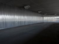 an industrial building features high ceiling and concrete flooring with a thin corrugated metal wall