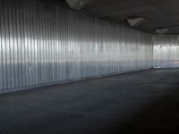 an industrial building features high ceiling and concrete flooring with a thin corrugated metal wall