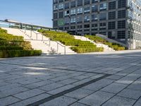 a large building with steps, trees and shrubs in the courtyard of a large urban park