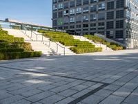 a large building with steps, trees and shrubs in the courtyard of a large urban park