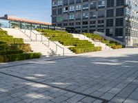 a large building with steps, trees and shrubs in the courtyard of a large urban park