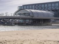 there is a train that is on the tracks going over the water by some sand