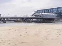 there is a train that is on the tracks going over the water by some sand