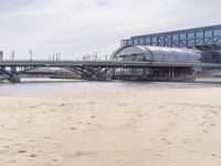 there is a train that is on the tracks going over the water by some sand