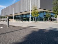 a large building sitting in front of a road next to a parking lot with trees