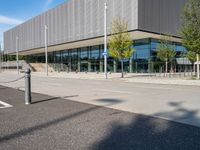 a large building sitting in front of a road next to a parking lot with trees