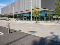 a large building sitting in front of a road next to a parking lot with trees