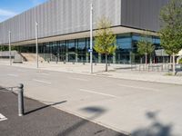 a large building sitting in front of a road next to a parking lot with trees