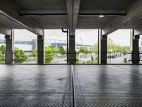 an empty parking garage with several windows open and trees in the distance under the canopy