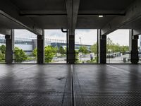 an empty parking garage with several windows open and trees in the distance under the canopy