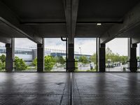 an empty parking garage with several windows open and trees in the distance under the canopy