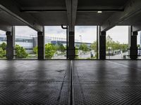 an empty parking garage with several windows open and trees in the distance under the canopy