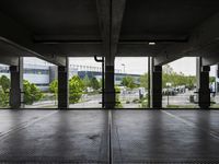 an empty parking garage with several windows open and trees in the distance under the canopy