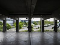 an empty parking garage with several windows open and trees in the distance under the canopy