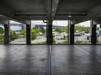 an empty parking garage with several windows open and trees in the distance under the canopy