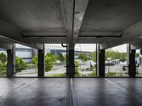 an empty parking garage with several windows open and trees in the distance under the canopy