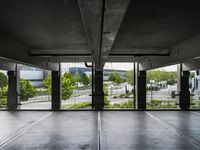 an empty parking garage with several windows open and trees in the distance under the canopy