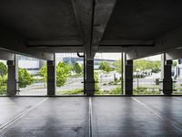 an empty parking garage with several windows open and trees in the distance under the canopy