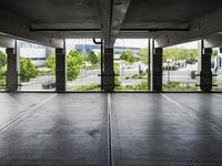 an empty parking garage with several windows open and trees in the distance under the canopy