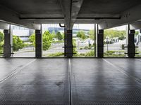 an empty parking garage with several windows open and trees in the distance under the canopy