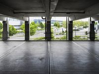 an empty parking garage with several windows open and trees in the distance under the canopy