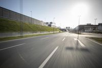 a long road next to an industrial area and parking lot with street lights on the side