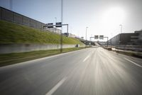 a long road next to an industrial area and parking lot with street lights on the side