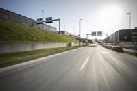 a long road next to an industrial area and parking lot with street lights on the side