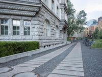 the driveway is lined with small shrubs and brick bricks and cement blocks and bricks that are next to the walkway