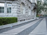 the driveway is lined with small shrubs and brick bricks and cement blocks and bricks that are next to the walkway