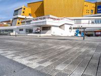 a large modern building next to a street in front of another one that is yellow