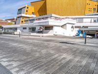 a large modern building next to a street in front of another one that is yellow