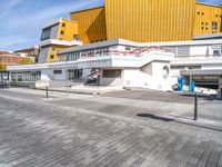 a large modern building next to a street in front of another one that is yellow