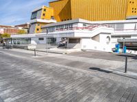 a large modern building next to a street in front of another one that is yellow