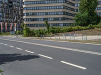 there is an empty street in front of a huge building under construction with trees around