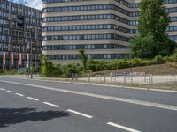there is an empty street in front of a huge building under construction with trees around