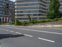 there is an empty street in front of a huge building under construction with trees around