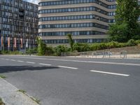 there is an empty street in front of a huge building under construction with trees around