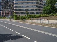 there is an empty street in front of a huge building under construction with trees around