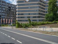 there is an empty street in front of a huge building under construction with trees around